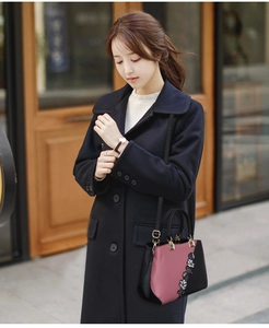 Close-up of color-block PU leather tote with floral embroidery and golden metal buckle