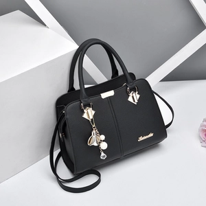Elegant black lychee leather handbag for women with gold hardware and floral pendant