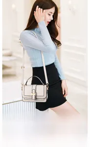 Detail of cream white textured leather crossbody bag with elegant gold buckle and strap