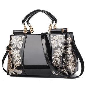 Glossy black patent leather handbag with floral sequin embroidery and gold hardware