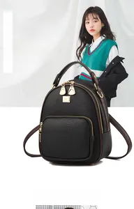 Close-up of black pebble leather mini backpack with gold hardware and logo detail
