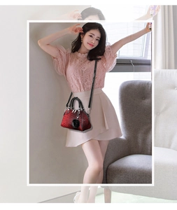 Close-up of red crocodile texture handbag with decorative rose charm and strap