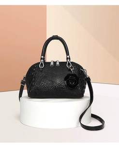 Detail of black crocodile texture handbag with rose pendant and dual zippers