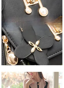 Detail of golden hardware and floral leather pendant on a black embroidered bucket bag