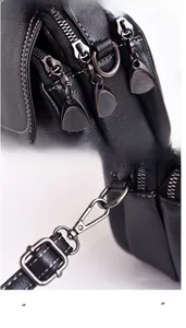 Détail d'un sac en cuir noir avec double fermeture éclair et crochets métalliques