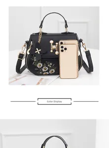 Detail of black embroidered bucket bag with daisy pattern and pearl accents with phone scale