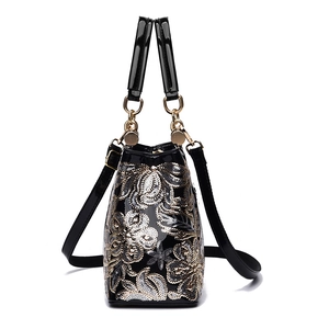 Glossy black handbag with intricate gold and silver floral embroidery and gold hardware