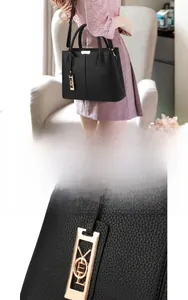 Detail of black lychee grain leather handbag featuring elegant gold metal hardware charms