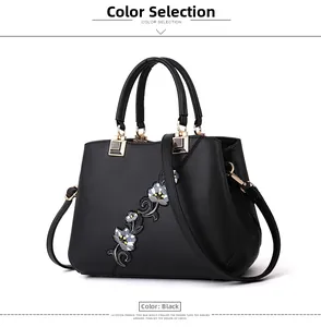 Close-up of black leather handbag featuring intricate floral embroidery and gold hardware