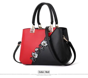 Detailed shot of two-tone handbag featuring red and black leather with floral embroidery