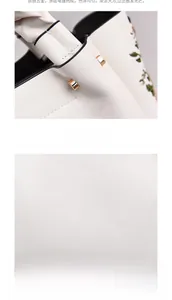 Detail of cream white PU handbag featuring golden hardware and elegant green embroidery
