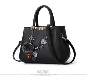 Detailed embroidery of grey flowers on a structured black leather handbag for women
