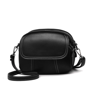 Petit sac rond noir en cuir avec surpiqûres blanches contrastées et trois poches zippées