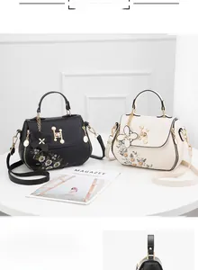 Close-up of floral embroidery and metallic H-lock detail on stylish ladies' handbags