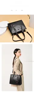 Detail of black textured leather handbag with gold rings and adjustable strap