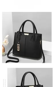 Close-up of black lychee grain leather handbag with gold hardware and removable shoulder strap