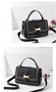 Close-up of black PU leather crossbody bag with gold H-buckle and white stitching details
