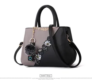Detail of embroidered floral patterns on grey and black leather patchwork handbag