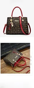 Détail du sac monogramme noir et doré avec poignée rouge et pendentif de chat