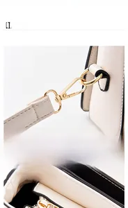 Detail of light gold hardware hooks and secure zipper closure on cream leather crossbody bag