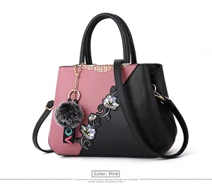 Detail of embroidered floral pattern on a rubber red and black luxury tote handbag