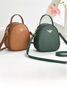 Detail of woven texture shoulder bags with gold bee metal accent and adjustable strap
