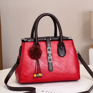 Détail d'un sac à main rouge grainé avec anses café et fermoir métallique élégant