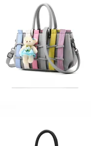 Detail of grey pebbled leather handbag with colorful woven stripes and a cute bear charm