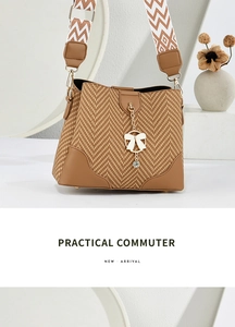 Close-up of brown woven bucket bag with herringbone fabric, leather trim, and bow charm