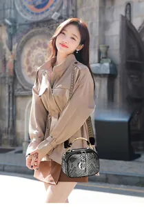 Detail of python-embossed leather texture and metallic charms on small lady handbag