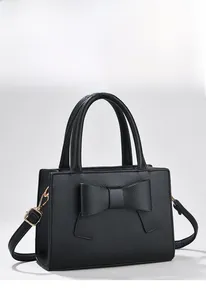 Détail du sac à main noir en cuir grainé avec grand nœud et crochets métalliques dorés