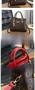 Détail du sac à main marron avec bordure rouge, breloque chat dorée et chaîne en métal