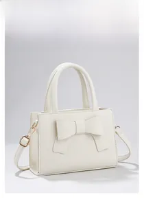 Détail du sac à main crème avec nœud, texture cuir grainé et bandoulière réglable