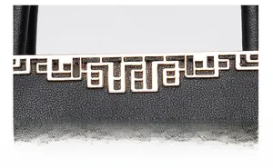 Macro shot of light gold geometric metal hardware on textured black leather handbag