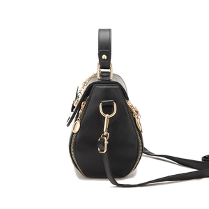 Minimalist black embroidered bucket bag with gold zippers and chain detail on white background