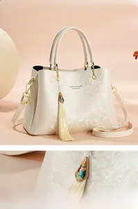 Gros plan du sac cabas beige en jacquard avec motifs floraux et pompon décoratif