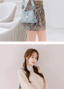Detail of grey herringbone bucket bag with geometric wide strap and golden bow charm