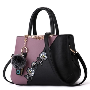 Elegant purple and black leather handbag with floral embroidery and gray pompom charm