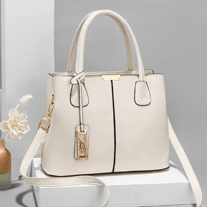 Minimalist beige lychee grain leather tote bag with gold hardware on white pedestal