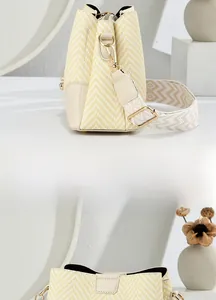 Detail of woven straw bucket bag featuring wide jacquard strap and golden metal hooks