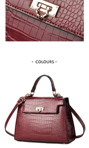 Close-up of crocodile pattern leather and gold lock detail on dark red Kelly bag