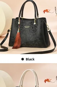 Détail du sac à main noir avec gaufrage floral et garnitures métalliques dorées