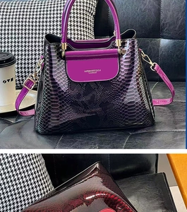 Détail du sac à main dégradé violet avec motif serpent sur un canapé en cuir noir