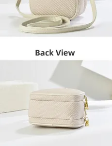 Back view of a beige textured fabric crossbody bag with multi-layer gold zippers