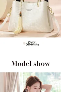 Détail du sac crème avec gaufrage floral, poignée en perles et pendentif à pompon