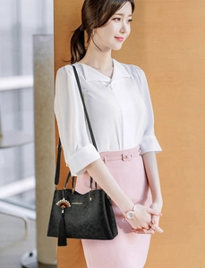 Black embossed leather handbag with floral pattern and gold tassel charm on a model