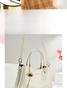 Detail of cream white handbag with embossed floral texture and red fan tassel charm