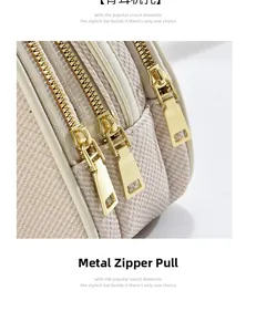 Close-up of triple gold metal zippers and woven texture on beige crossbody bag