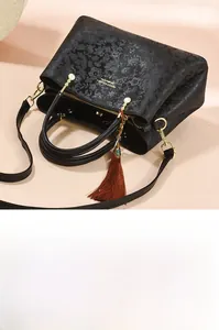 Détails d'un sac à main en cuir gaufré floral noir avec pendentif à pompon en soie