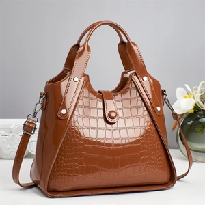 Close-up of brown crocodile embossed leather handbag with glossy finish and silver studs